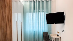 A hotel room with a bed, a desk, a chair, a TV, and a window with curtains. - Casa DeDa Charme - Luxury Design on the Trabocchi Coast (Fossacesia)
