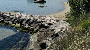A coastal scene with a rocky shoreline, a pier extending into calm waters, and a distant cityscape. - Casa DeDa Charme - Luxury Design on the Trabocchi Coast (Fossacesia)