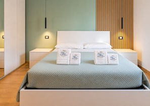 Een moderne slaapkamer met een bed, witte nachtkastjes en een houten paneelwand.