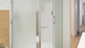Une salle de bain moderne avec une douche à l’italienne en verre, un meuble-lavabo en bois et un lavabo blanc.