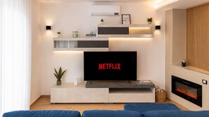 A modern living room with a flat-screen TV, a fireplace, and a blue sofa. - Casa DeDa Charme - Luxury Design on the Trabocchi Coast (Fossacesia)