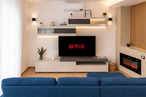 Un salon moderne avec un téléviseur à écran plat, une cheminée et un canapé bleu.