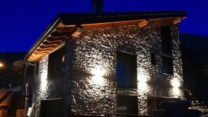 Un edificio de piedra con un porche de madera y dos ventanas iluminadas.