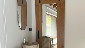 Un baño con tocador de madera, un espejo grande, toallero y puerta corredera que da a la zona de ducha.