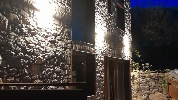 Un edificio de piedra con una terraza de madera y un muro de piedra.