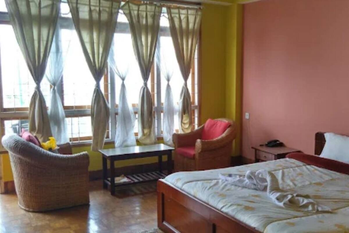 Ein Schlafzimmer mit einem Bett, einem Sessel, einem Tisch und einem Bild an der Wand.