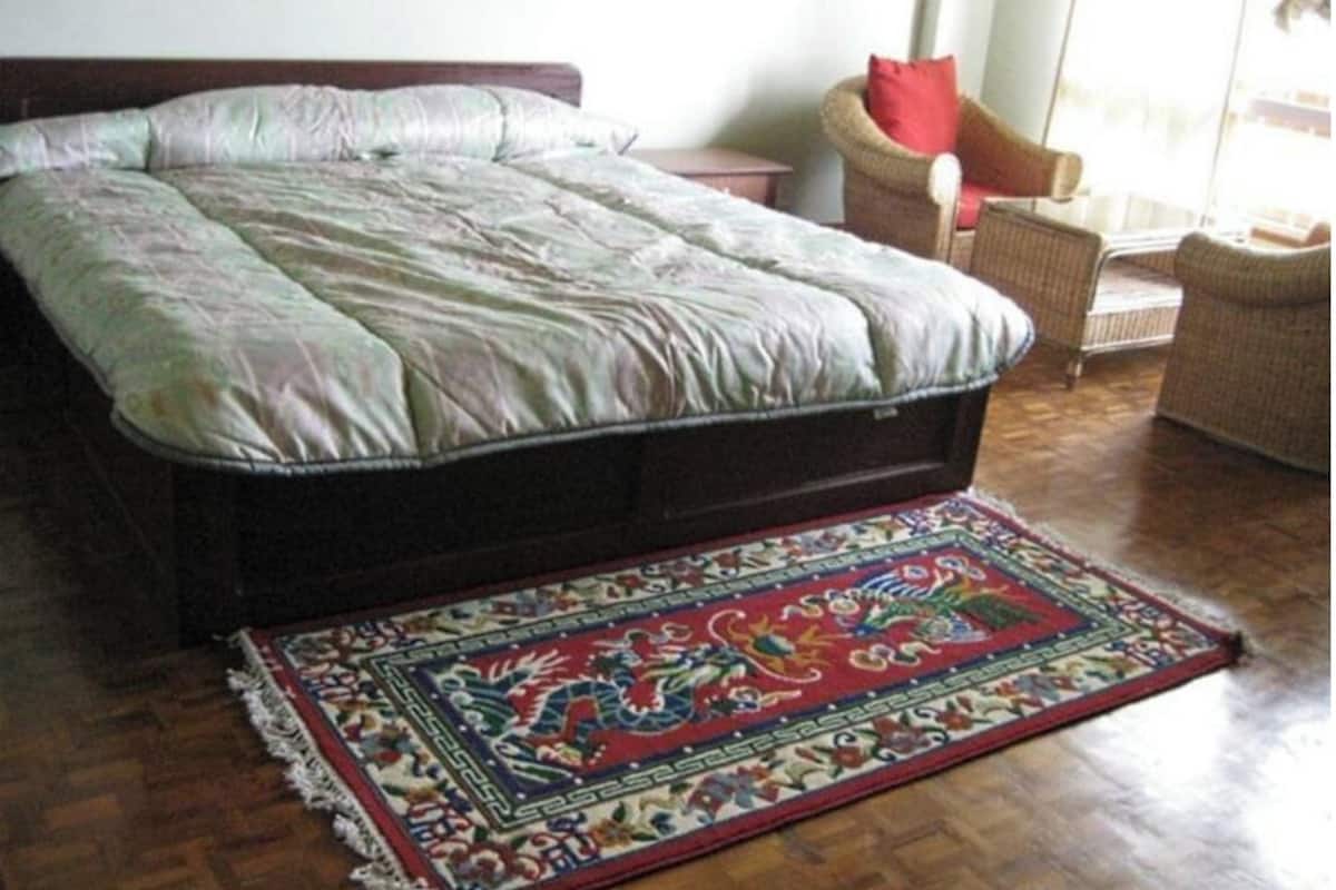 Ein Schlafzimmer mit einem großen Bett, einem farbenfrohen Teppich und Korbmöbeln.