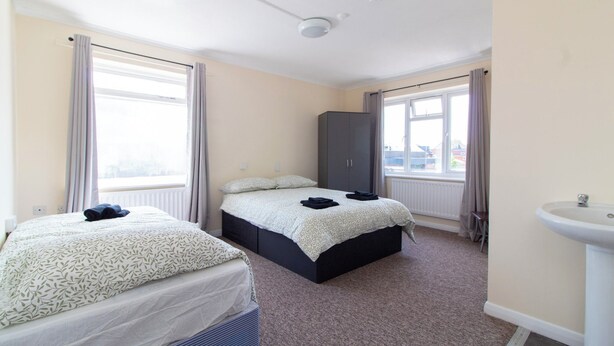 A hotel room with two beds, a wardrobe, a radiator, and a sink. - Brookvale Guest House Room 12 (Southampton)