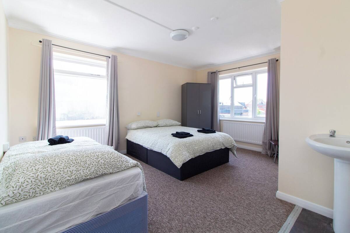 Una habitación de hotel con dos camas, un armario, un radiador y un lavabo.