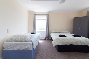 A room with two beds, a wardrobe, and a window with curtains. - Brookvale Guest House Room 12 (Southampton)