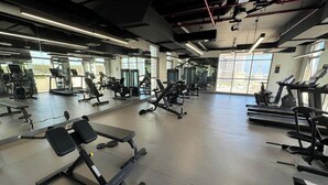Ein geräumiger Fitnessraum mit unterschiedlichen Trainingsgeräten, großen Fenstern und modernem Industriedesign.