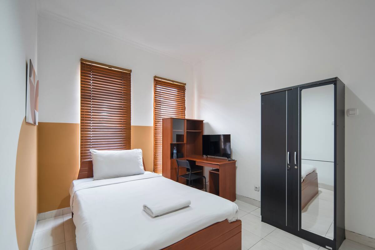 Una habitación de hotel con cama, escritorio, televisor y armario.
