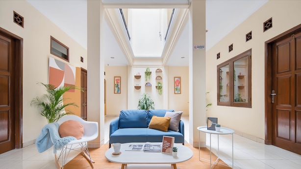 A modern living room with a blue sofa, a white coffee table, and a rocking chair. There is a skylight above, and the room has wooden flooring.