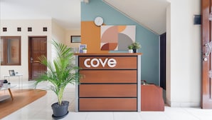 A reception desk with the word "cove" on it, a clock, and a potted plant.