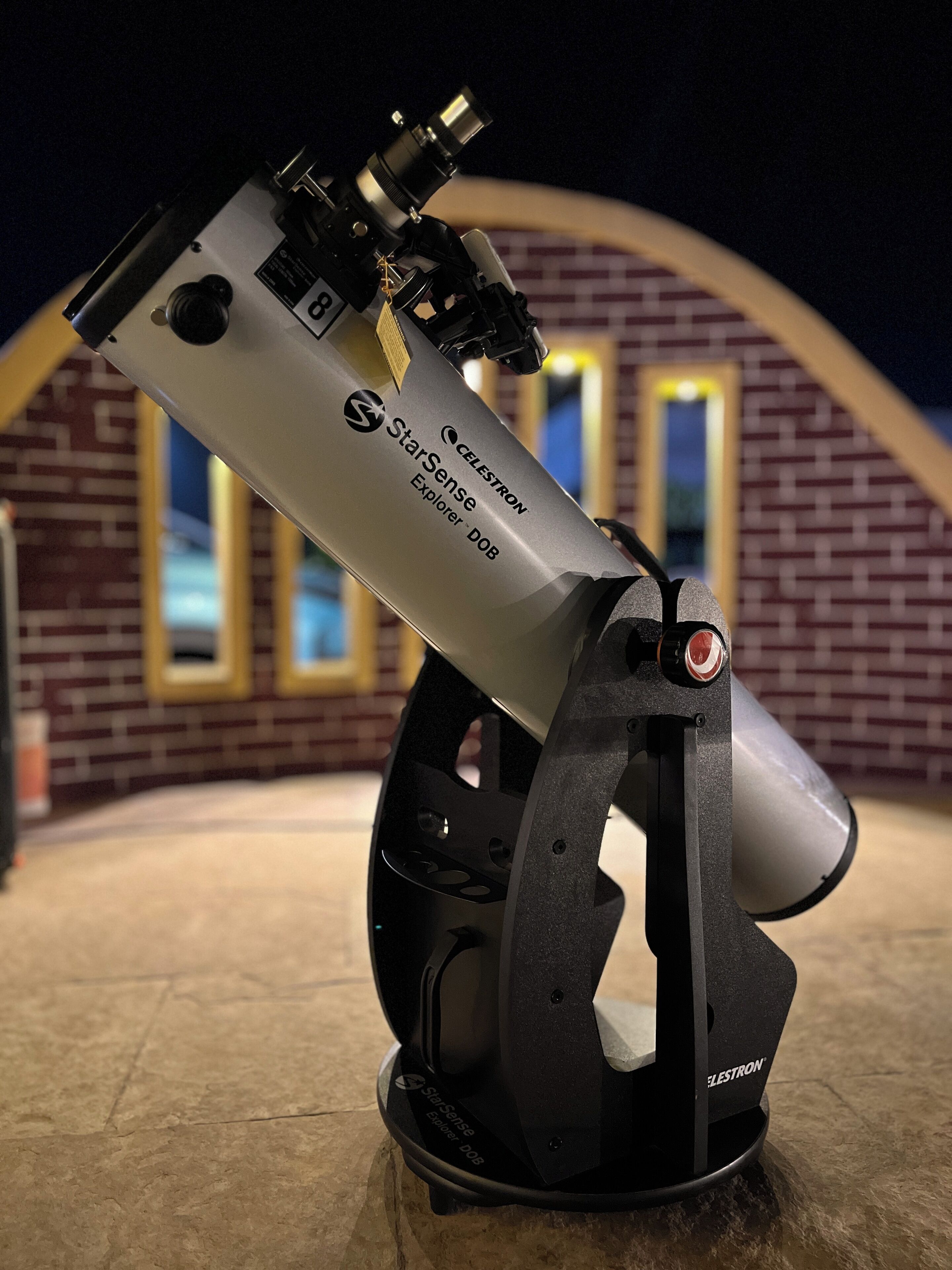 A telescope with the brand 'StarSense Explorer DOB' mounted on a stand.