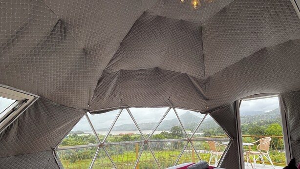 Un dormitorio con un ventanal grande, una cama y vistas a un paisaje verde.