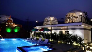 Un hotel moderno con piscina, sillones de descanso y sombrillas.