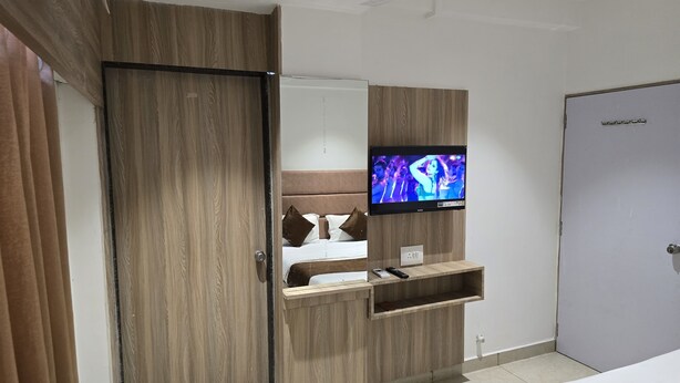 Ein Hotelzimmer mit einem Holzschrank, einem an einer Holzhilfe angebrachten Fernseher und einer Tür.