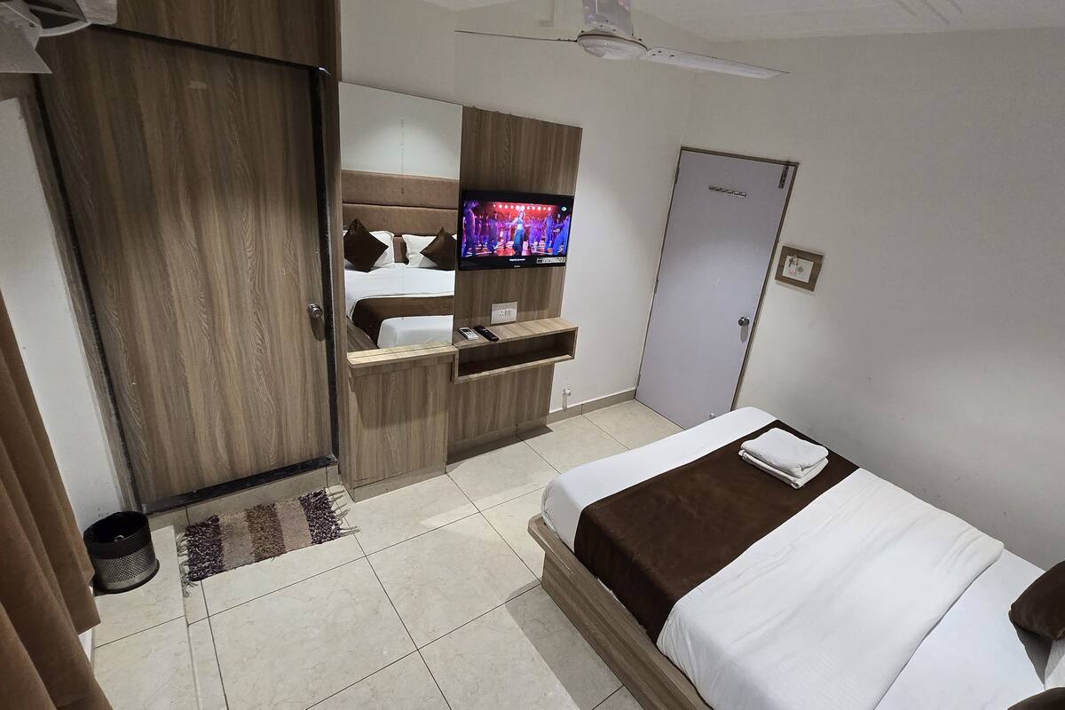 A hotel room with a bed, a TV, a wardrobe, and a desk.