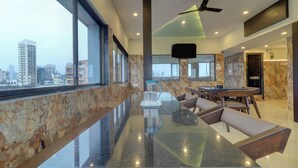 A modern dining area with a marble countertop, seating, and a city view. - Hotel Victoria Park (Mumbai)
