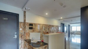 A hotel reception area with a marble reception desk, a digital check-in station, and a door labeled "802". - Hotel Victoria Park (Mumbai)