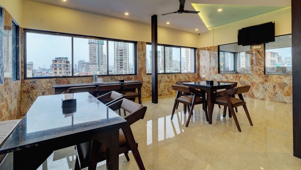 A modern conference room with marble walls, large windows offering city views, and a flat-screen TV mounted on the wall. - Hotel Victoria Park (Mumbai)