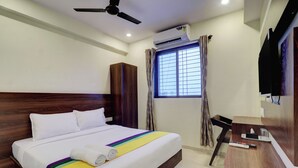 A hotel room with a bed, a desk, a TV, and an air conditioning unit. - Hotel Victoria Park (Mumbai)