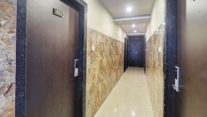 A hallway with marble walls and doors labeled with room numbers. - Hotel Victoria Park (Mumbai)