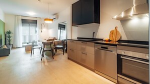 Una cocina moderna con electrodomésticos de acero inoxidable, un comedor con mesa y sillas, y un ventanal con cortinas.