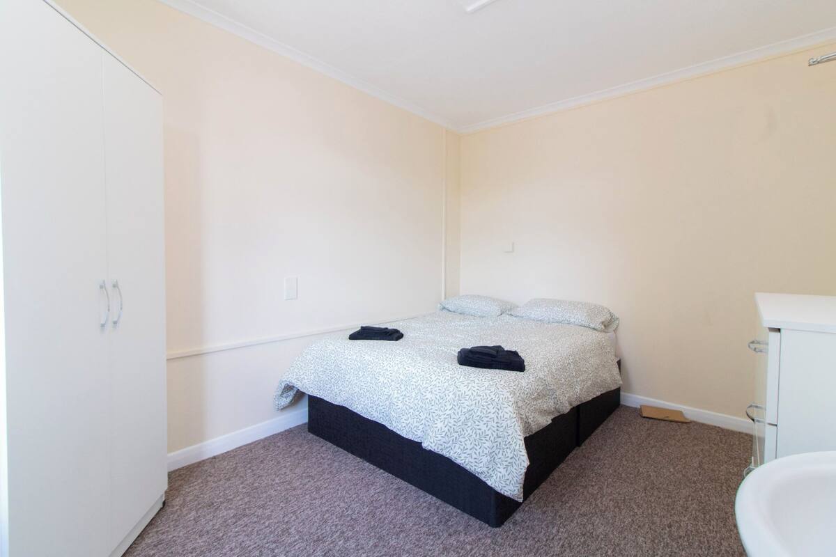 Een kleine, schone kamer met een bed, een witte garderobe en een badkamer.