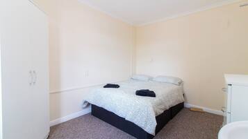 A small, clean room with a bed, a white wardrobe, and a bathroom.