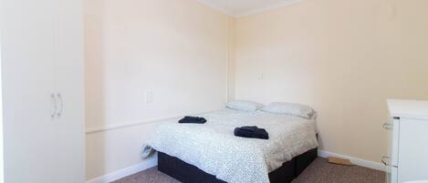Una habitación pequeña y limpia con cama, un armario blanco y baño.
