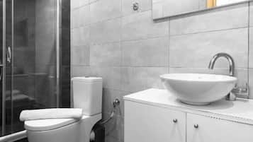 Un baño moderno con cabina de ducha de vidrio, inodoro blanco y lavabo con espejo.