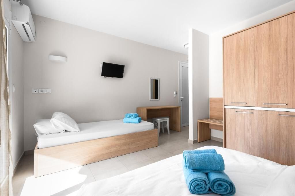 Una habitación de hotel moderna con cama, escritorio, televisor y armario.