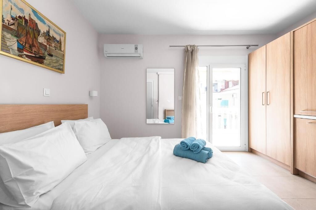 Habitación de hotel con cama, un cuadro en la pared, aire acondicionado, espejo y vistas al exterior.