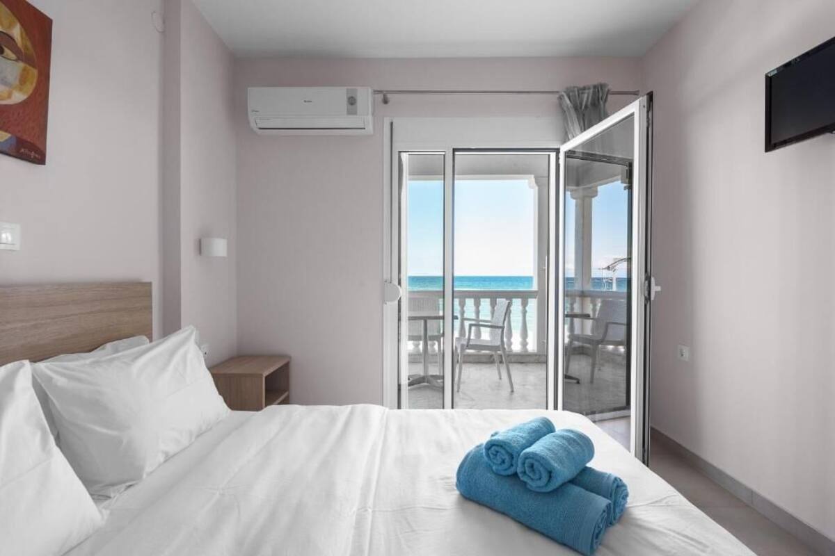 Habitación de hotel con cama, mesita de noche, televisor y balcón con vista al mar.