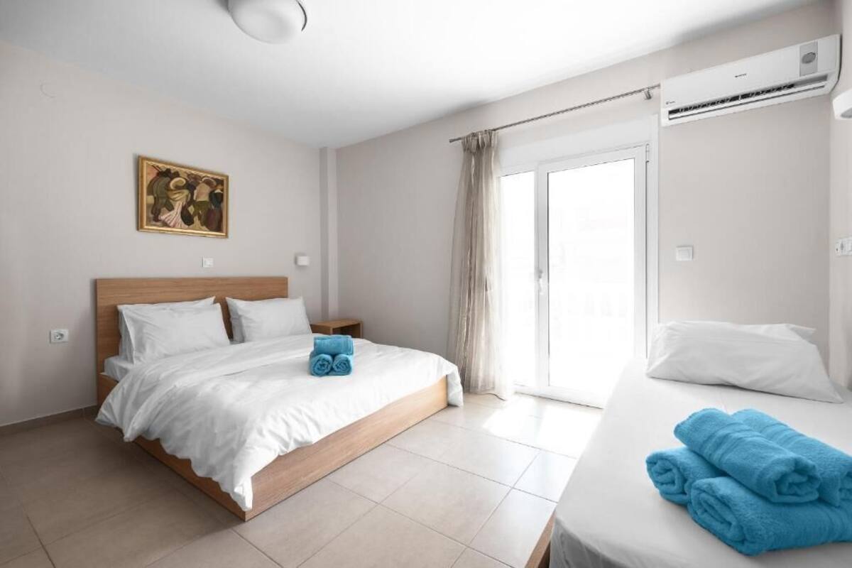 Una habitación de hotel moderna con una cama grande, una cama más pequeña, un cuadro en la pared y un equipo de aire acondicionado.