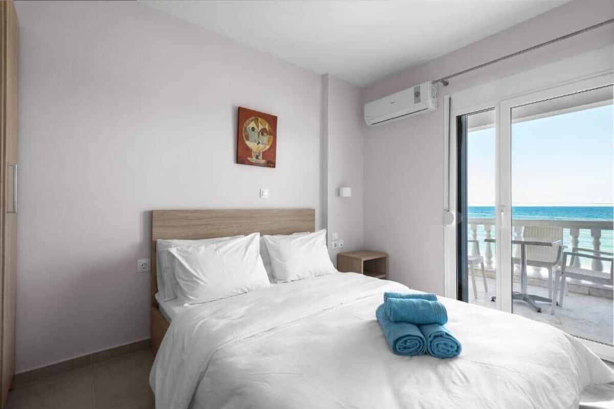 Habitación de hotel con cama, un cuadro en la pared y vista al mar desde el balcón.