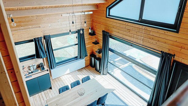 A wooden interior with a large window, a staircase, and a seating area. - Chalet "Les Alpages (Durbuy)