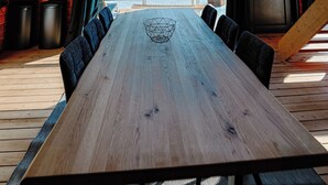 A wooden dining table with chairs, a hanging light fixture, and large windows. - Chalet "Les Alpages (Durbuy)