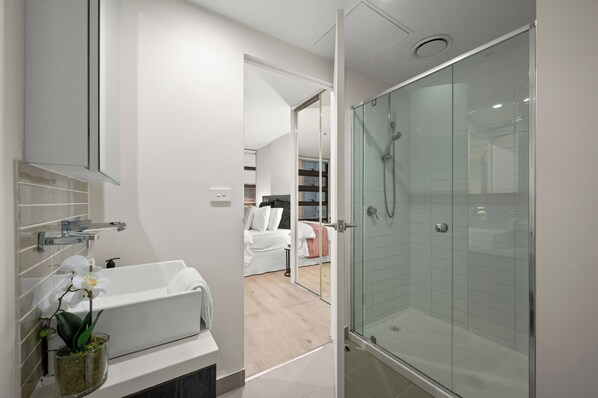 Ein modernes Badezimmer mit einer gläsernen Duschkabine, einer weißen Badewanne und einer Topforchidee.