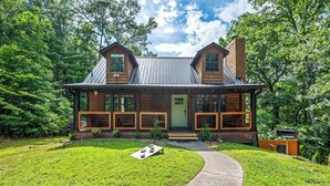 A wooden cabin with a porch, a front door, and a small front yard with a pathway leading to the entrance. - Dog OK | Hot Tub + Game Rm | Dollywood (Pigeon Forge)