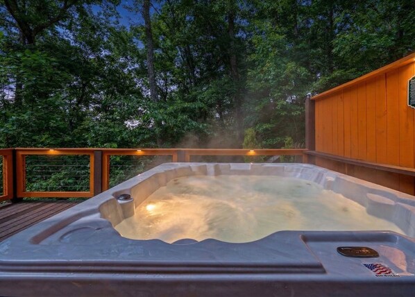 A hot tub surrounded by a wooden deck and trees.