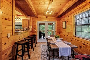 A wooden cabin interior with a dining area, bar, and large windows. - Dog OK | Hot Tub + Game Rm | Dollywood (Pigeon Forge)