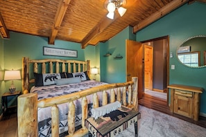 A rustic bedroom with a wooden bed frame, a sign reading "Great Smoky Mountains Tennessee," and a mirror on the wall.