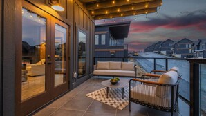 A modern outdoor balcony with a sofa, a small table with fruit, and a baby crib. - 10BR Luxury | 2 Cabins | Rooftop Lounges | Indoor Pools | Hot Tubs | Walk to Water Park | Sleeps 44 (Sevierville)
