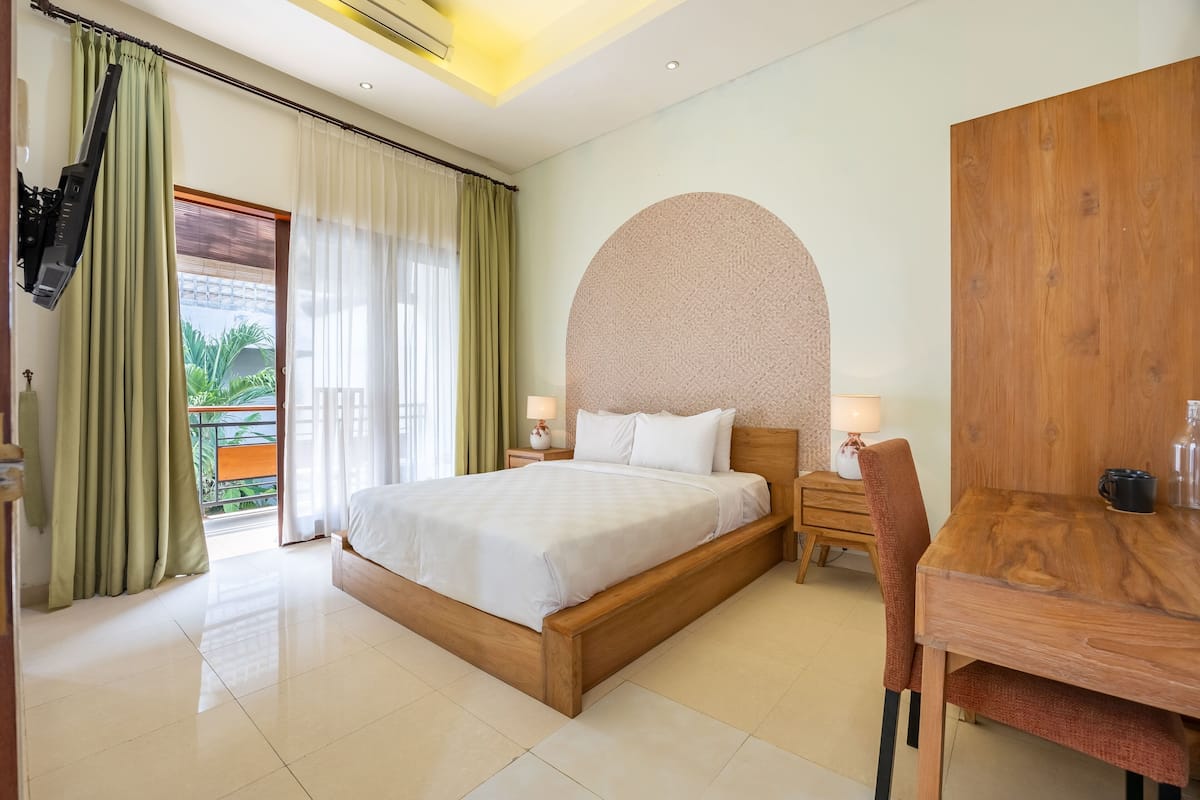 A hotel room with a bed, a desk, and a large window with curtains.