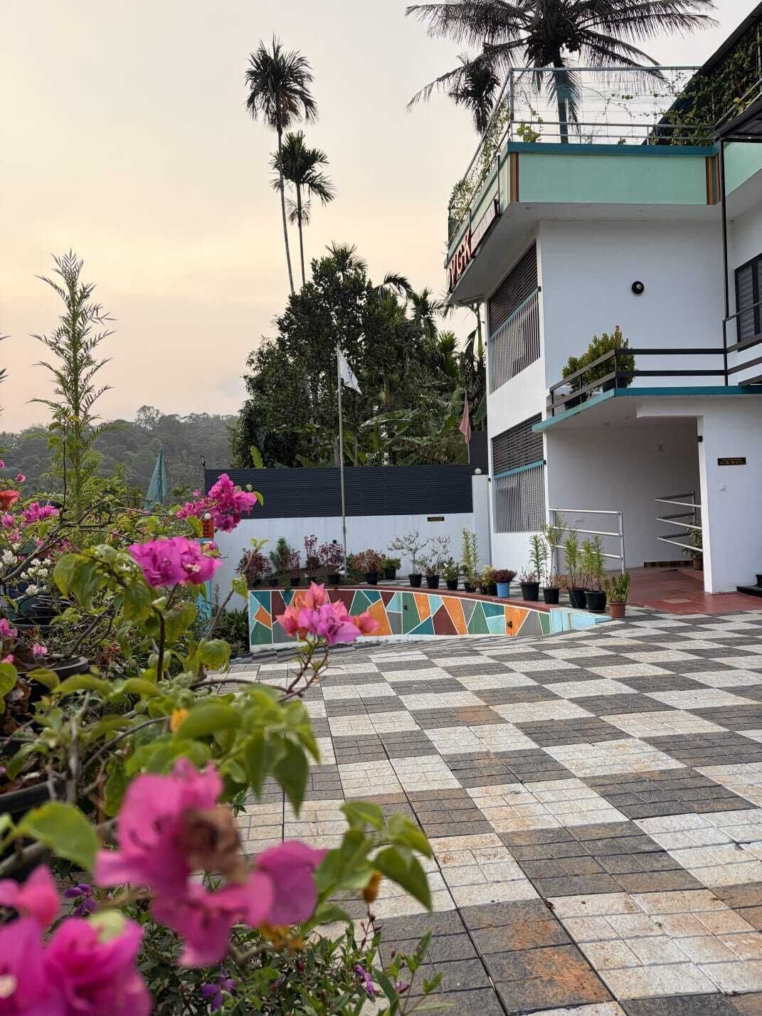 A building with a checkered floor, surrounded by potted plants and flowers.