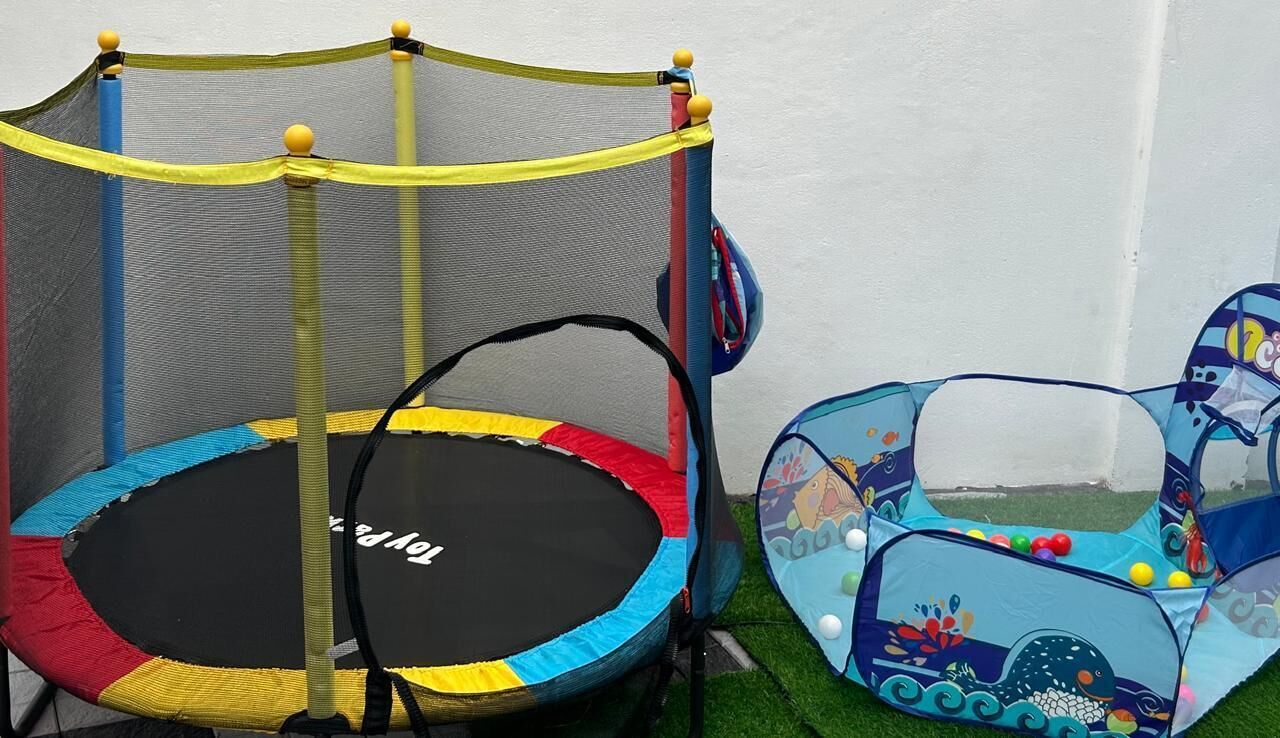 A trampoline with a safety net and a small play tent with a marine theme.