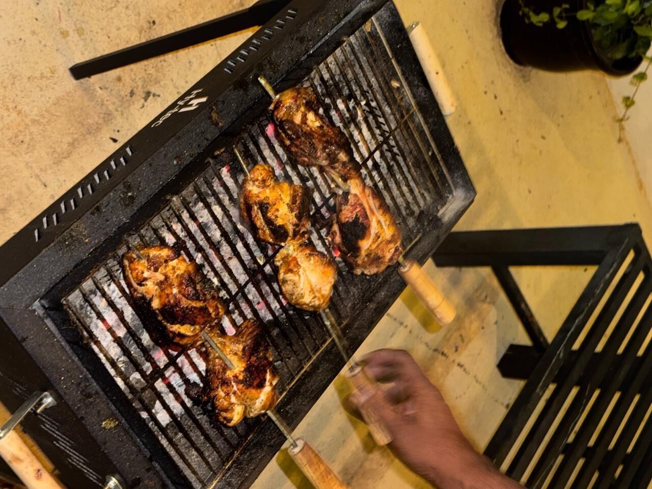 A person grilling chicken on a barbecue grill.